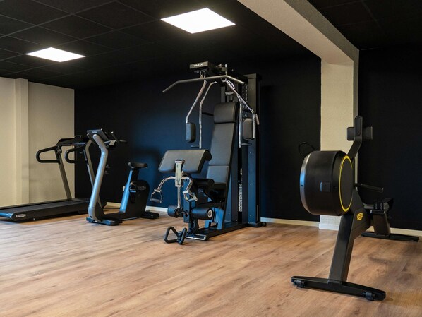 A gym with exercise equipment, a treadmill, and a squat rack. - ibis Styles Bordeaux Sud (Villenave-d'Ornon)