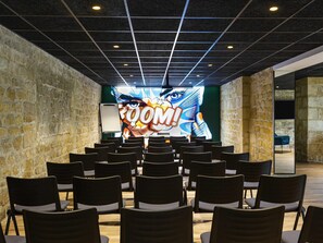 Une salle de conférence avec des rangées de chaises disposées face à un grand écran affichant un graphique.