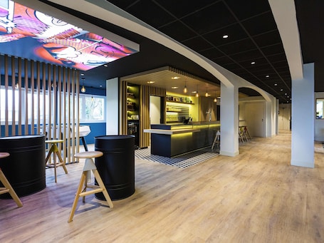 A modern interior with a bar area, seating, and a checkered floor pattern.. ibis Styles Bordeaux Sud