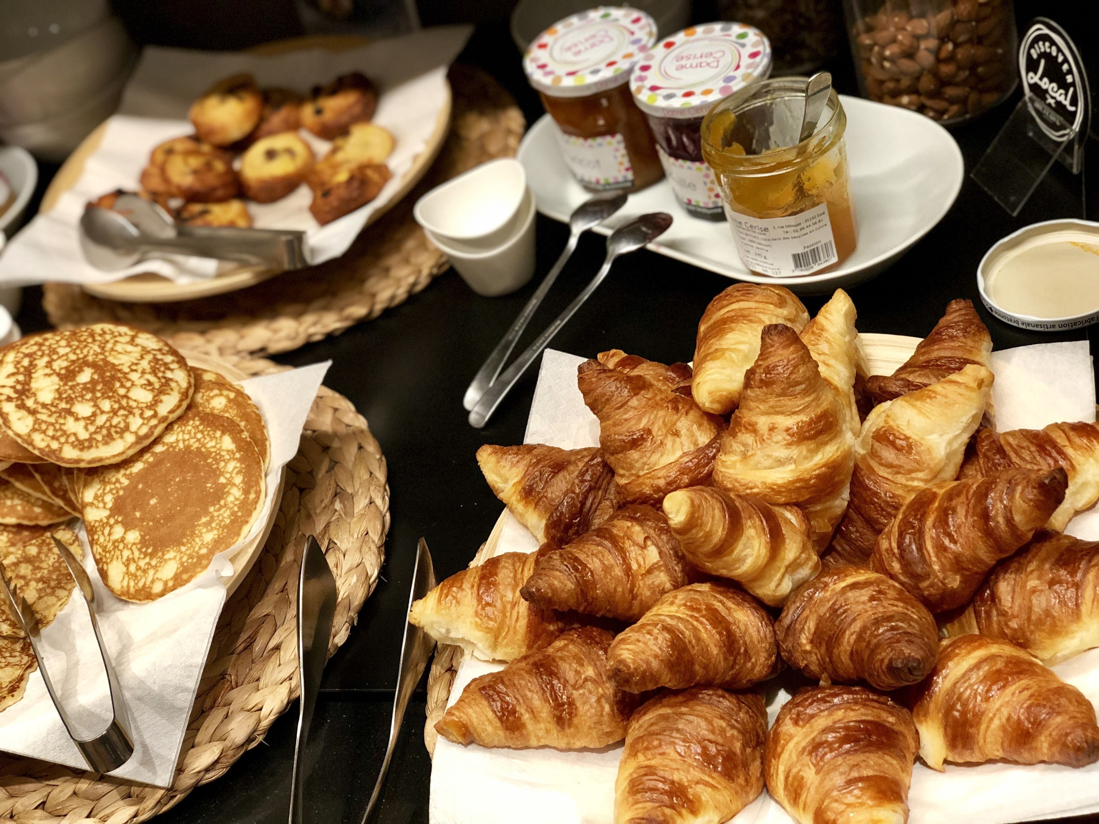 Un buffet de petit-déjeuner proposant des crêpes, des croissants et divers accompagnements.