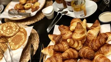Un buffet de petit-déjeuner proposant des crêpes, des croissants et divers accompagnements.