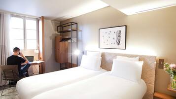 Una habitación de hotel con dos camas, un escritorio con una computadora portátil, una silla y un armario.
