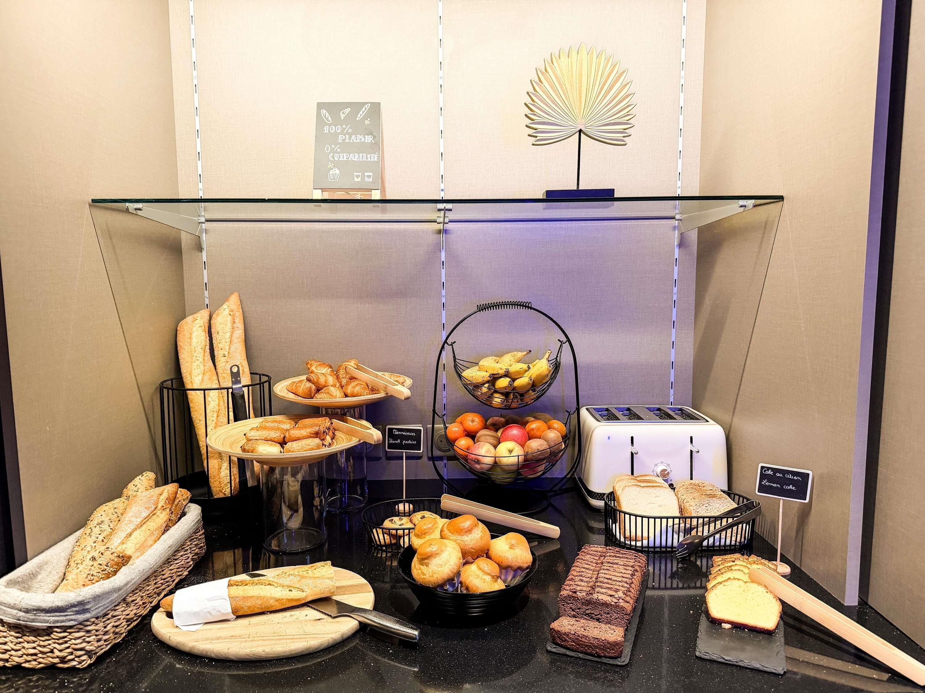 Un bufé de desayuno con panes, bollería, frutas y un tostador.