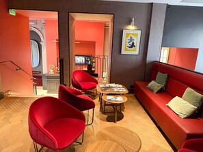 A modern interior with red seating, a wooden floor, and a framed artwork on the wall.