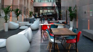 A modern indoor courtyard with seating areas, tables, and potted plants.