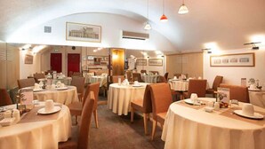 Un comedor de hotel con mesas redondas, sillas y un ambiente cálido y acogedor.