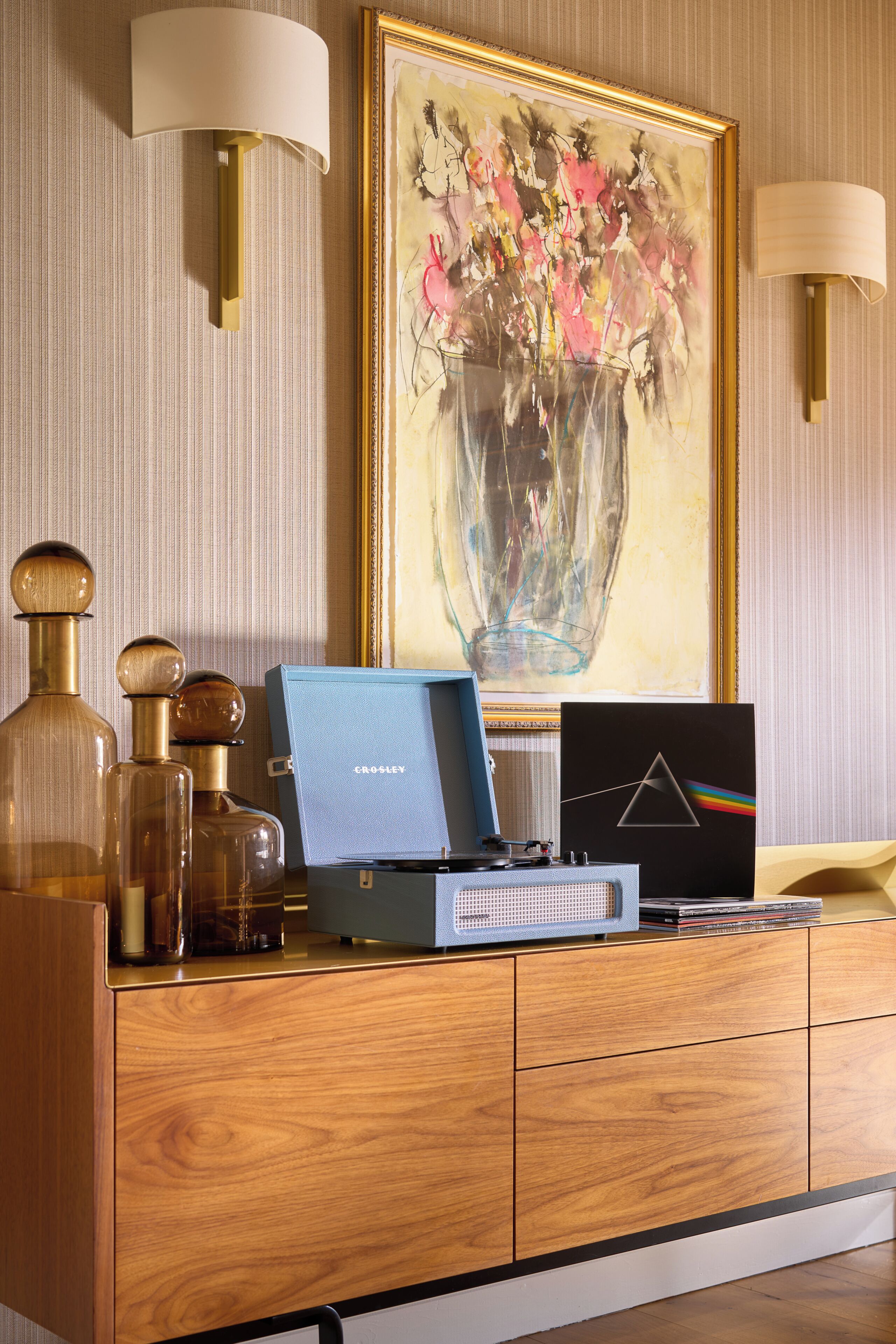 A wooden cabinet with a blue box labeled 'Crosley,' a computer monitor, and decorative bottles.