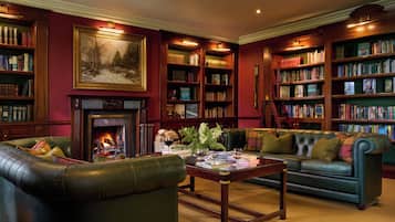 Eine Bibliothek mit Ledersofas, einem Kamin und Bücherregalen voller Bücher.