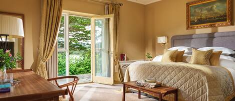 A bedroom with a bed, a desk, a chair, a table, a chandelier, and a painting on the wall.