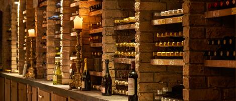 A wine cellar with wooden shelves and bottles, including a prominent bottle labeled "Chardonnay 2010".
