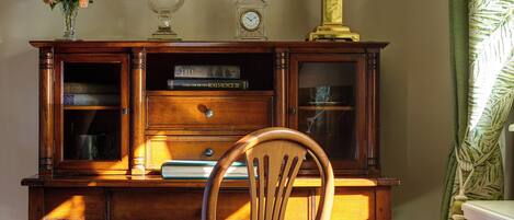 A wooden desk with a lamp, a chair, and a framed picture on the wall.