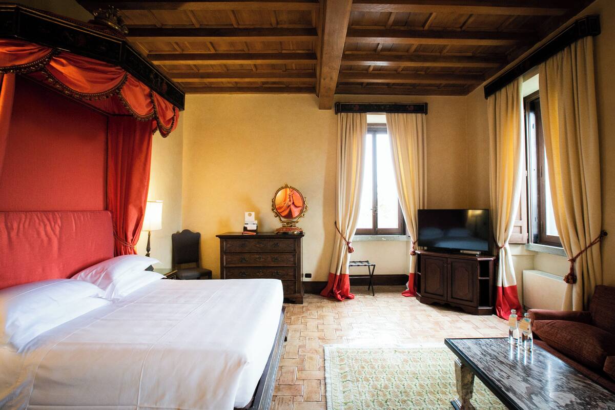 A hotel room with a large bed, a television, a desk, and a sofa.