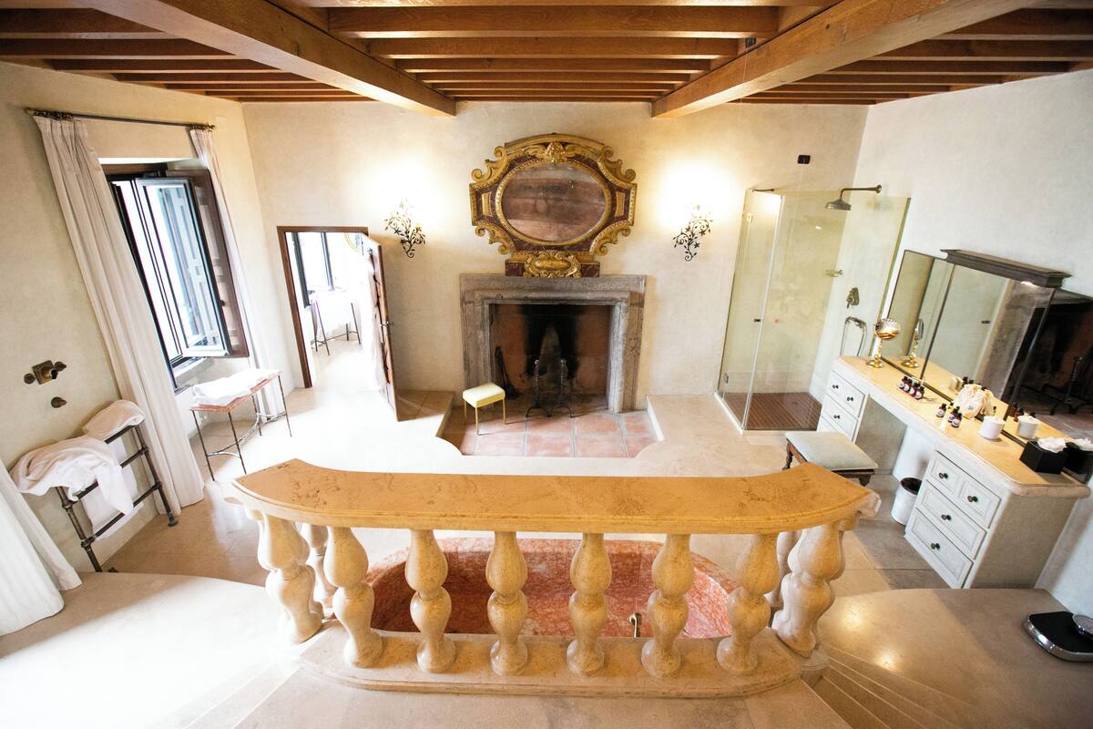 A room with a fireplace, a mirror, a wooden bench, and a small table.