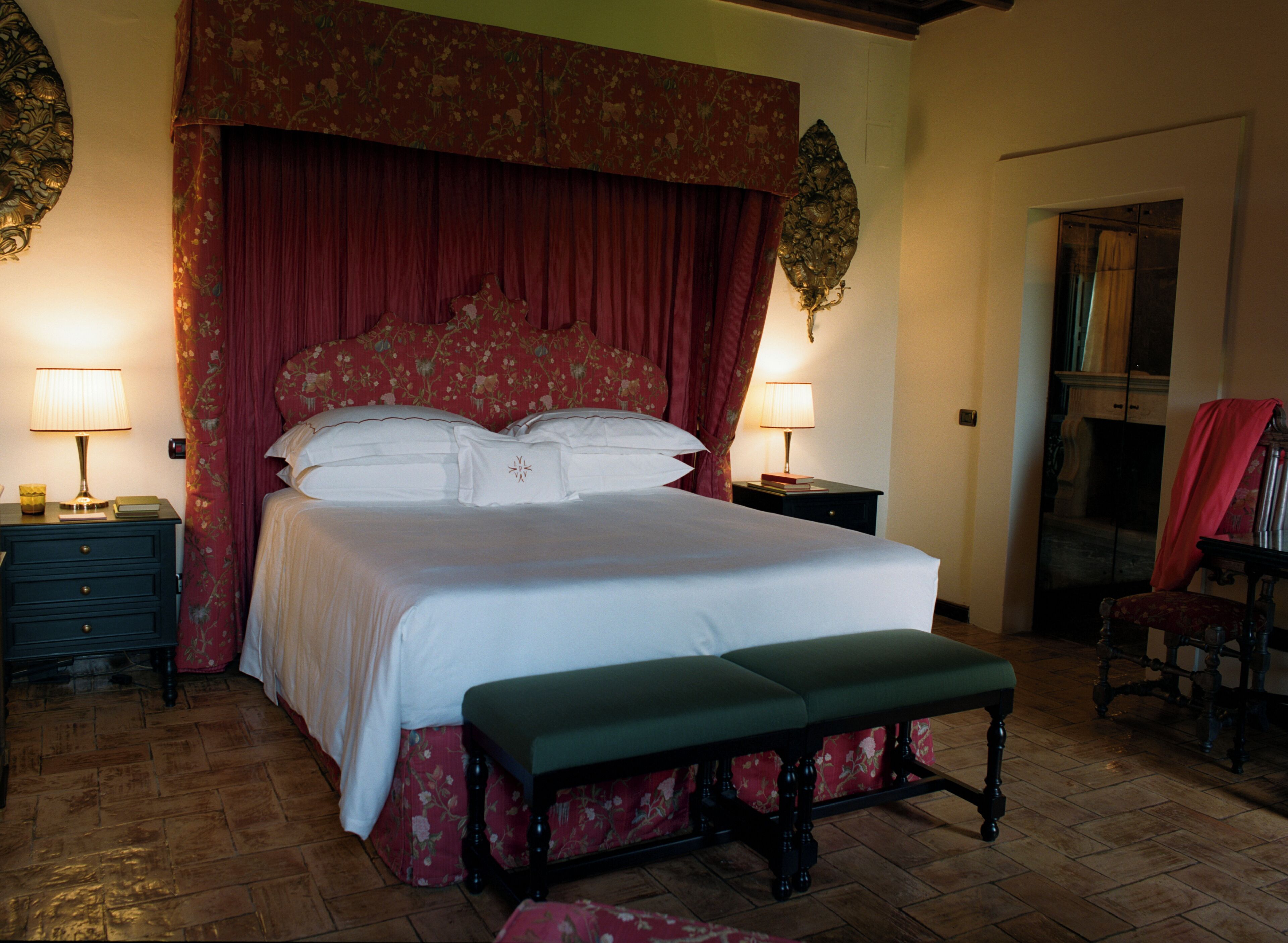 Une chambre à coucher avec un grand lit, deux tables de chevet avec des lampes, un banc et une chaise.