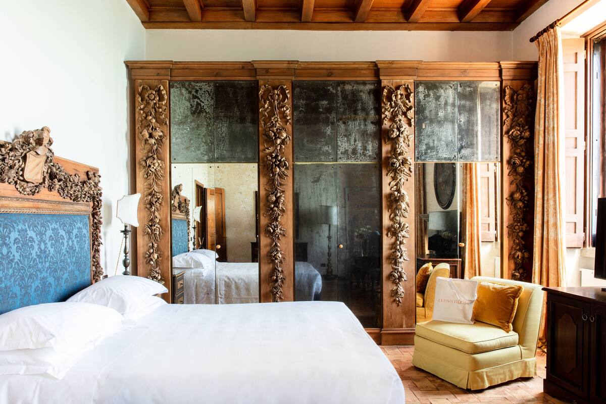 A bedroom with a large bed, a sofa, a wardrobe, and a mirror.