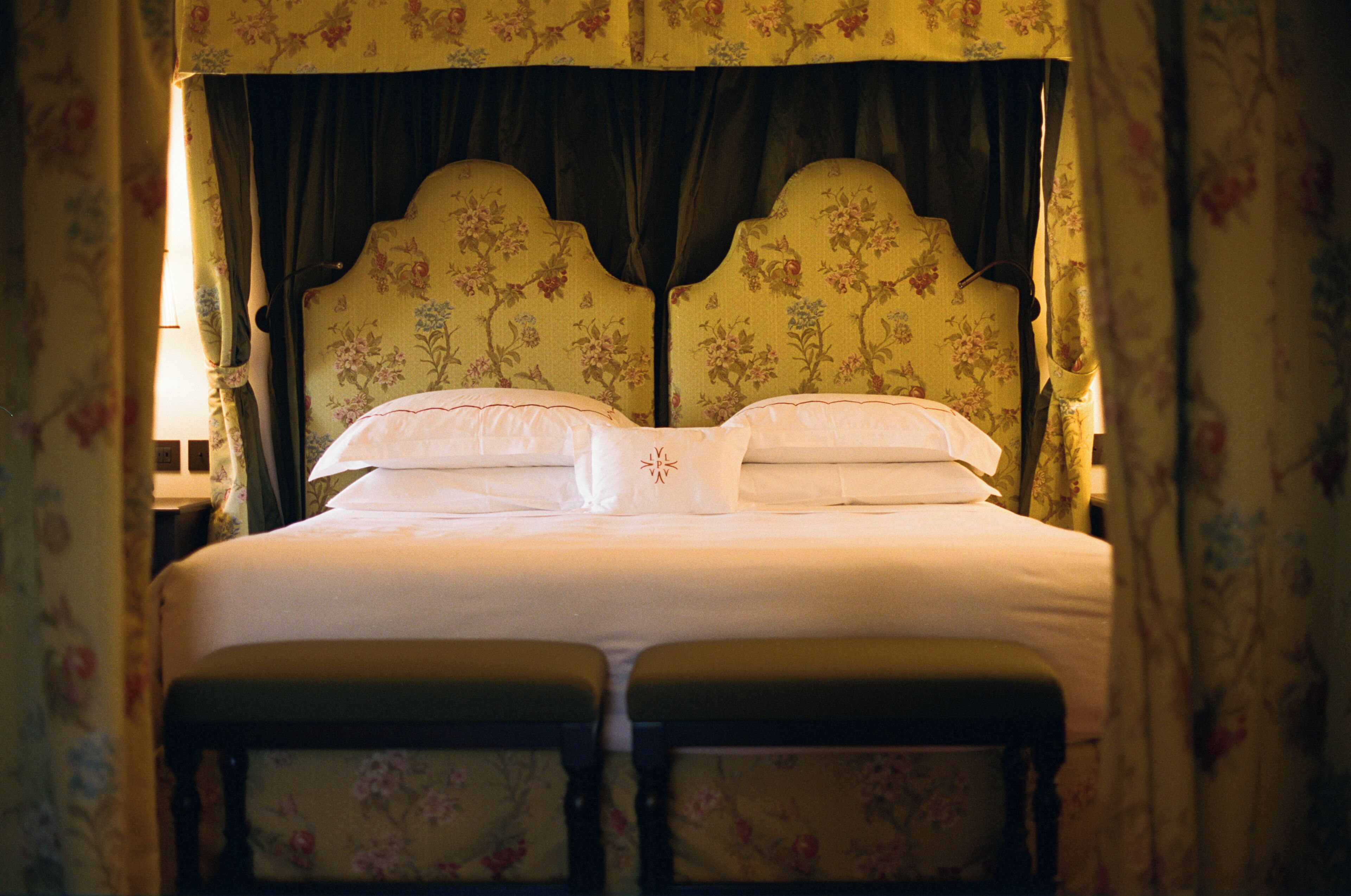 A bed with a floral headboard, two pillows, and a pair of matching nightstands.