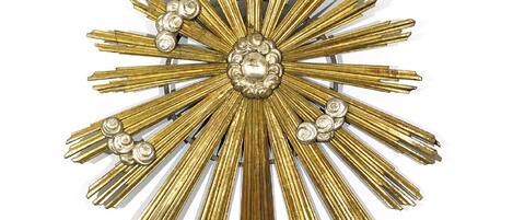 A decorative sunburst wall piece with a central spherical element and radiating golden strips.