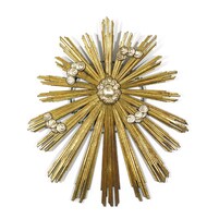 Een decoratief zonitemuurdecoratie met een centraal bolvormig element en uitstralende gouden stroken.