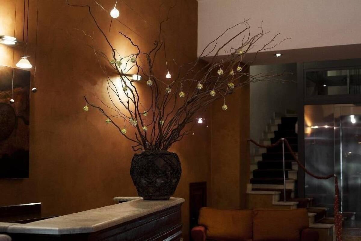 A modern interior with a decorative branch in a vase, a staircase, and a reception area.