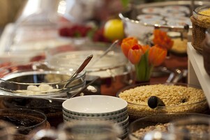 A buffet with various food items and a decorative vase with orange tulips.