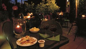 An outdoor dining area with tables, chairs, candles, and a variety of food and drinks. - Hotel Columbia (Rome)