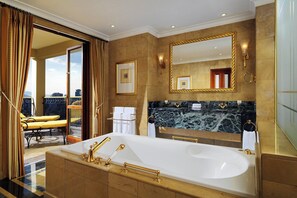 A luxurious bathroom with a large bathtub, gold fixtures, and a marble countertop.