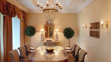 A formal dining room with a large oval table, six chairs, a chandelier, wall-mounted lamps, and framed pictures.