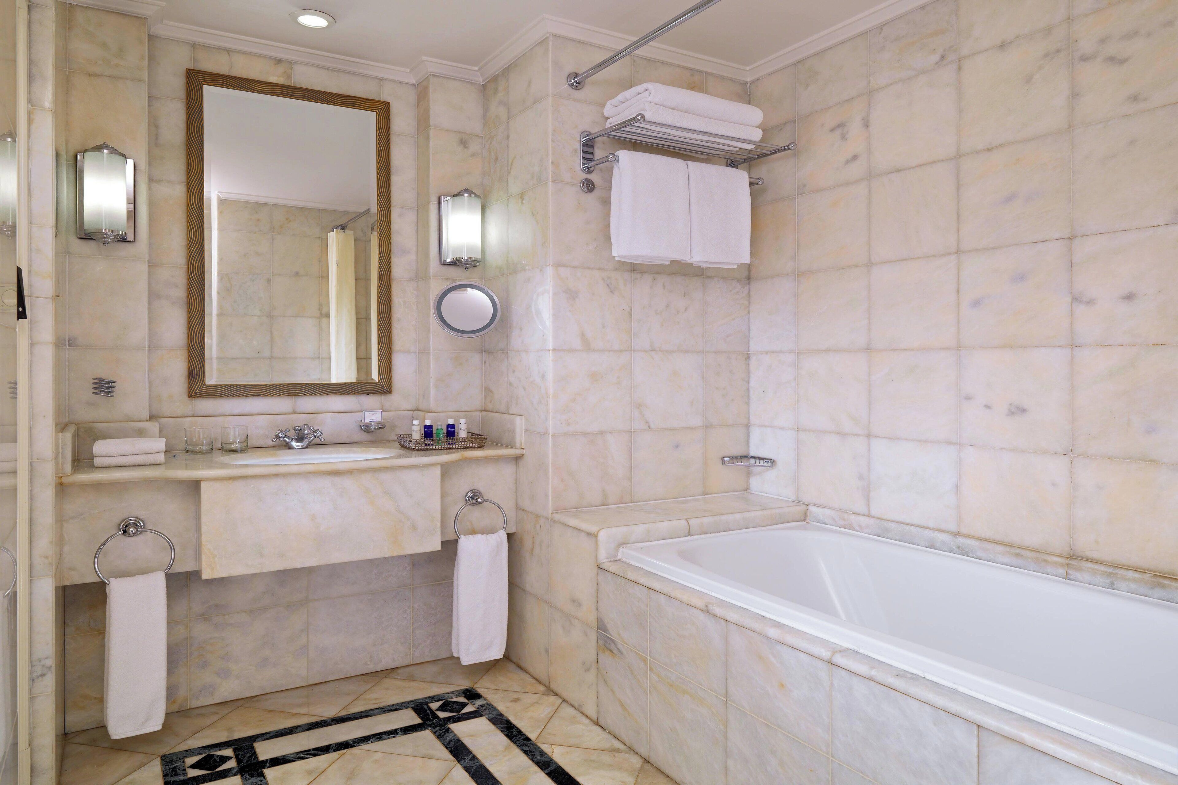 Un bany amb una banyera, un mirall gran, un lavabo amb una pica i un assecador de tovalloles.