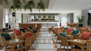A spacious lobby with wicker furniture, a bar area, and hanging plants.