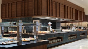A buffet setup with various food items, a chef, and a modern kitchen area.