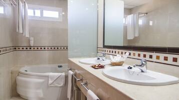 Un baño moderno con bañera, dos lavamanos, un espejo grande y una ventana.