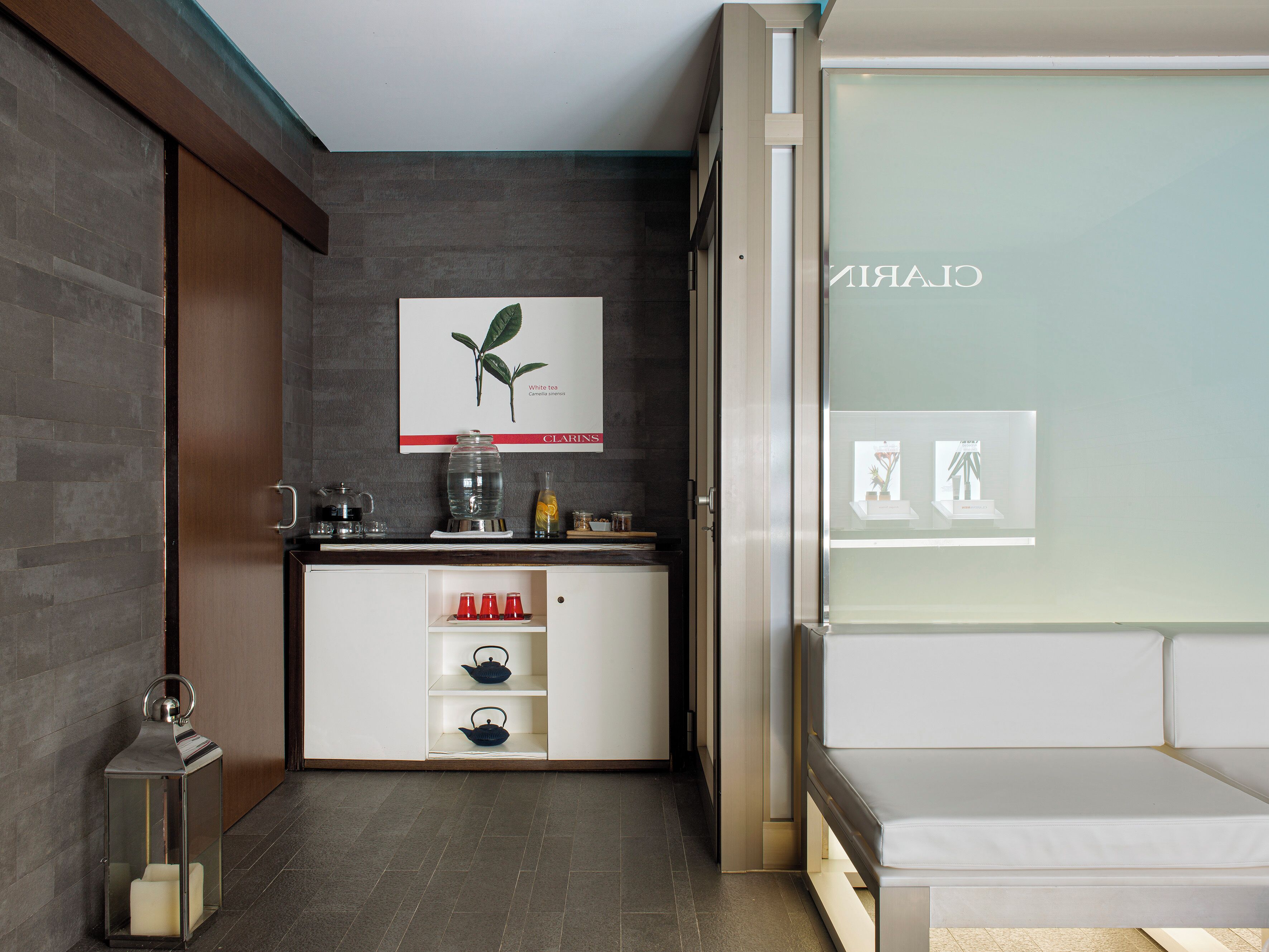 A modern room with a kitchen area, a white sofa, and a framed botanical illustration on the wall.