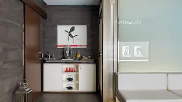A modern room with a kitchen area, a white sofa, and a framed botanical illustration on the wall.