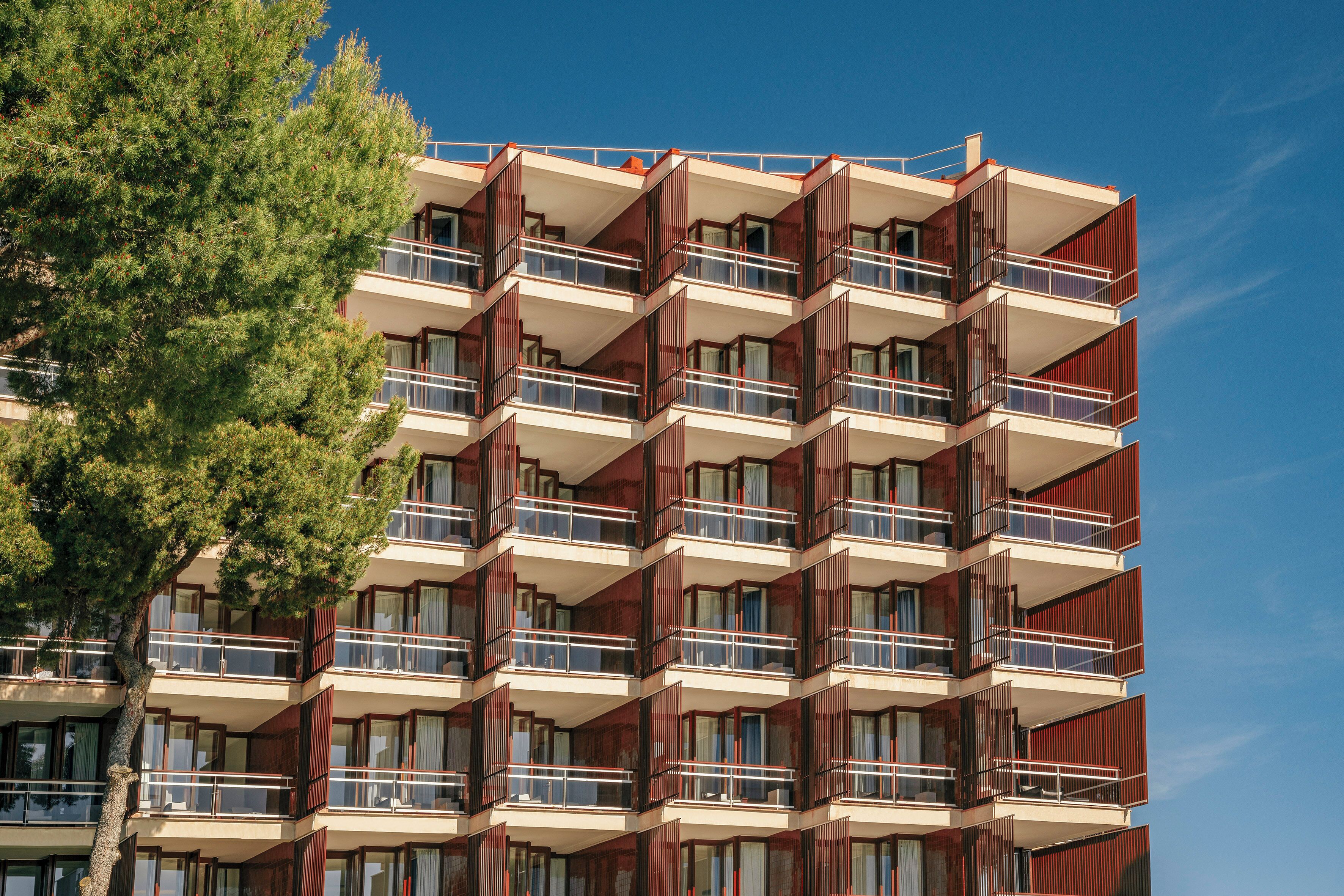 Un edificio de varios pisos con balcones, ventanas grandes y cielo despejado.