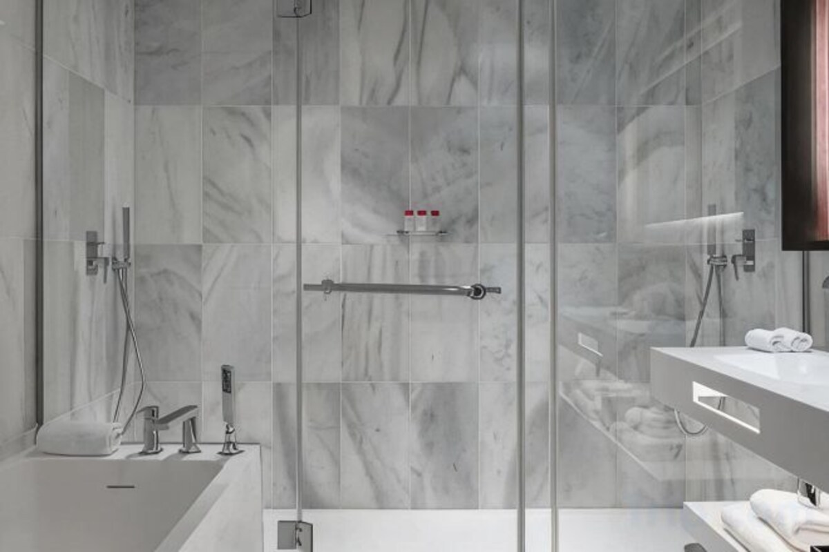 A modern bathroom with a glass shower enclosure, a vanity with a mirror, and a towel rack.