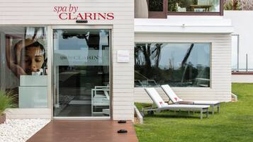 Un spa de Clarins con diseño moderno, entrada de vidrio y sillones de lounge al aire libre.