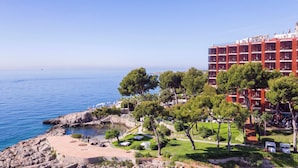 A coastal hotel with clear blue waters, a rocky shoreline, and a well-maintained garden with trees. - Hotel de Mar Gran Meliá - The Leading Hotels of the World (Calvia)