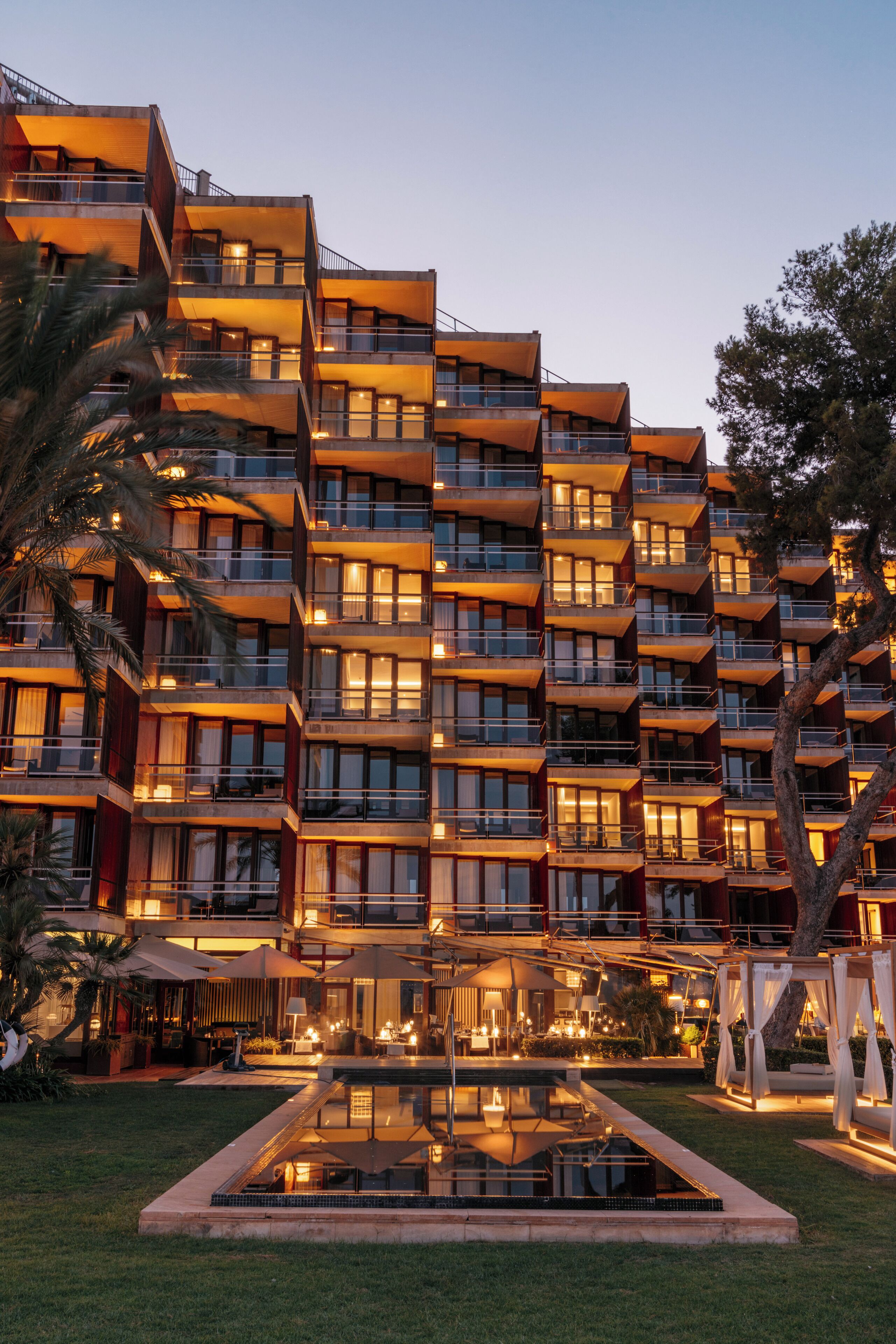 A multi-story hotel with balconies, a swimming pool, and outdoor seating areas.