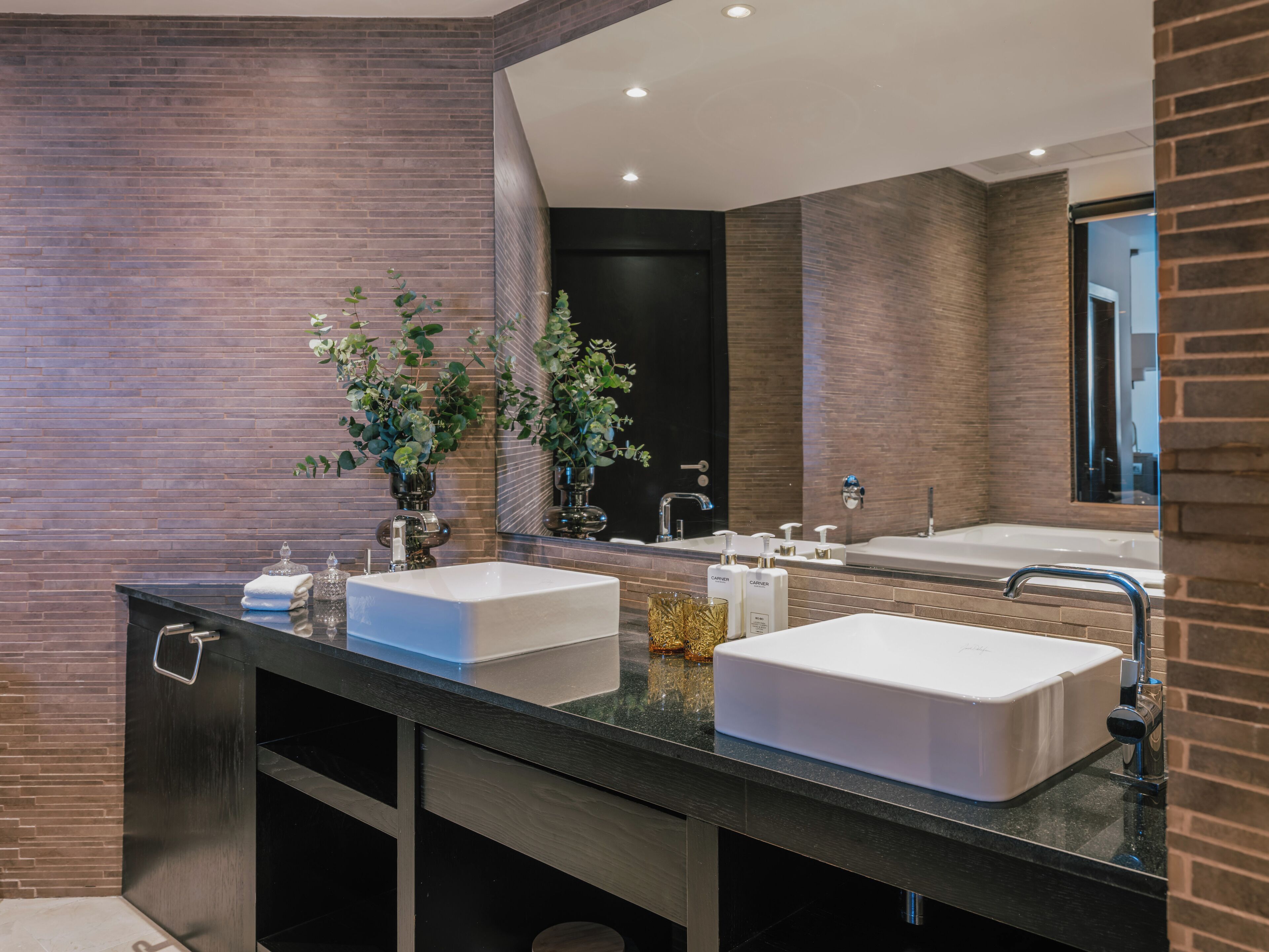 A modern bathroom with two sinks, a large mirror, and a dark countertop.