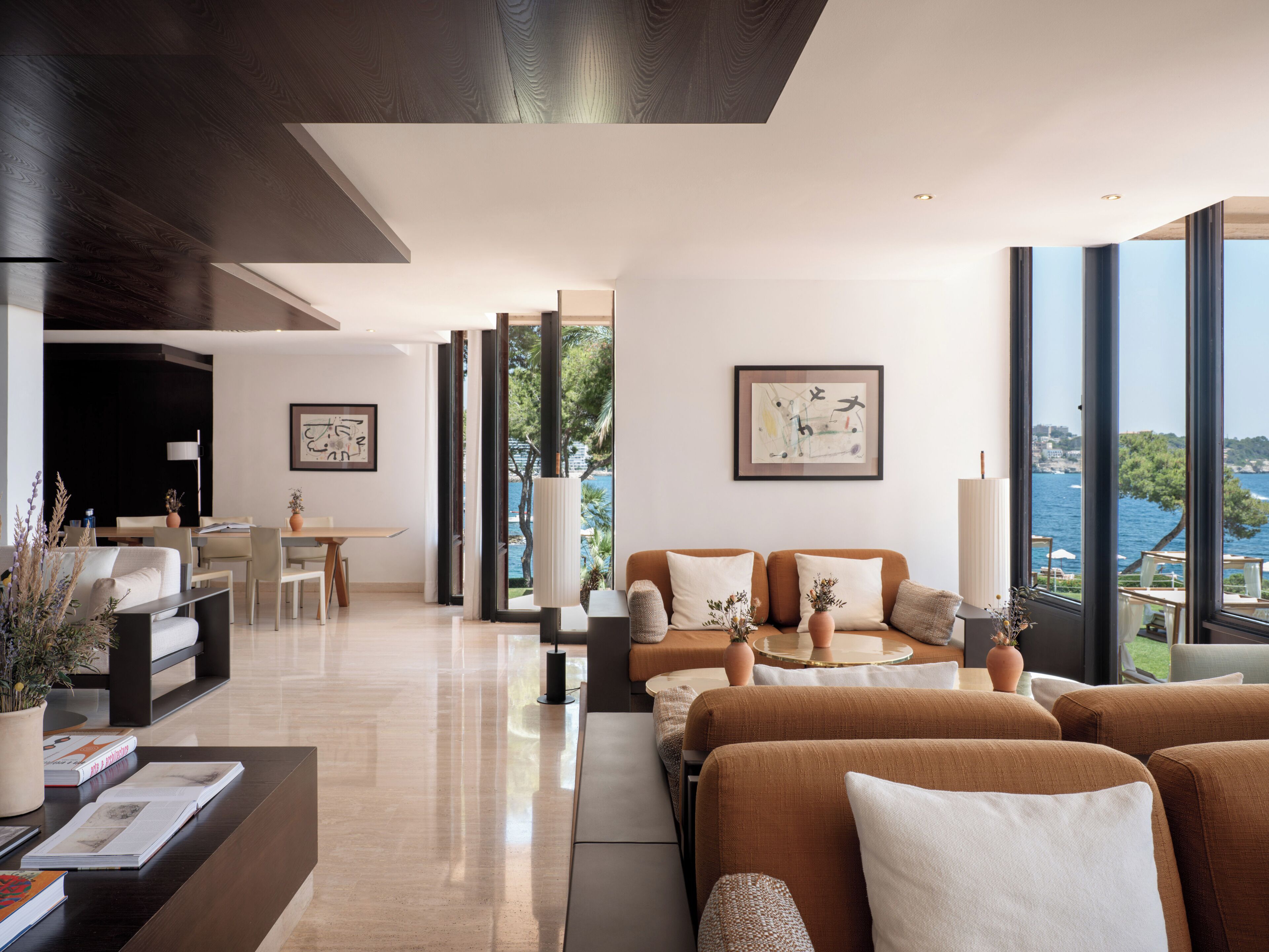 Un salon moderne comprenant un ensemble de canapés, un coin repas et une vue sur la mer.