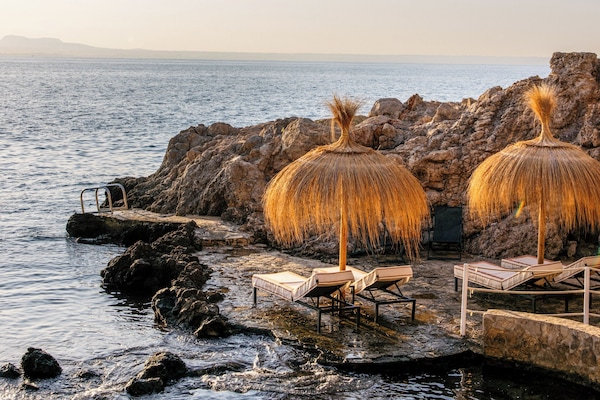 Na praia, areia branca, espreguiçadeiras, guarda-sóis