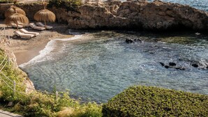 A rocky coastline with clear blue water, a sandy beach, and several sun loungers with umbrellas. - Hotel de Mar Gran Meliá - The Leading Hotels of the World (Calvia)