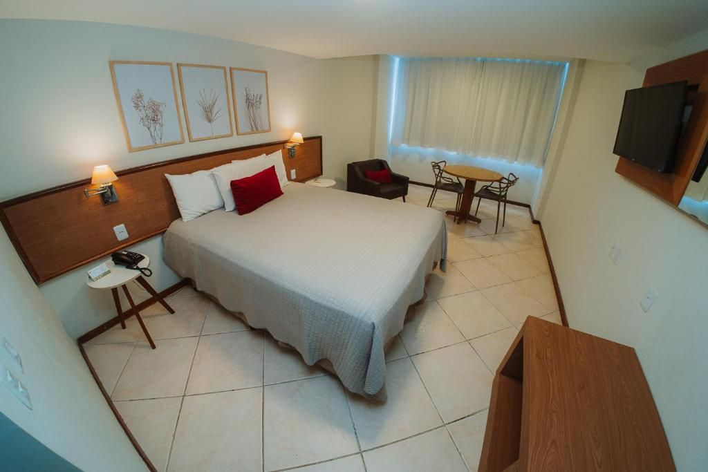 Ein Hotelzimmer mit Bett, Nachttisch, Lampe, Stuhl, Schreibtisch und Fernseher.