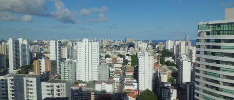 A cityscape with high-rise buildings, a clear sky, and a distant view of the sea.