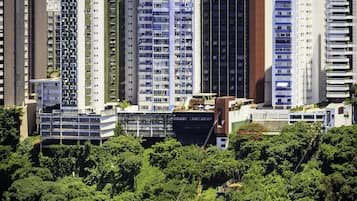 Un complejo de edificios altos con varios pisos, rodeado de abundante vegetación y una masa de agua con barcos.