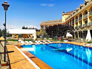 Una piscina al aire libre de temporada, sombrillas, tumbonas