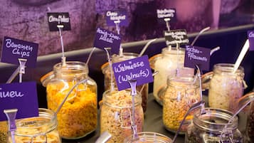 A variety of food items in jars with labels, including chips, cornflakes, cheese crisp, and walnuts.