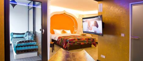 Habitación de hotel con cama, televisión, puerta corredera y vistas al exterior.