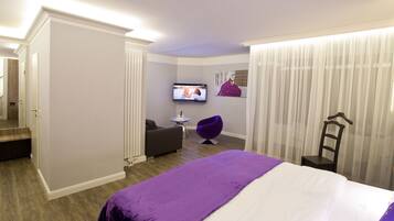 A hotel room with a bed, a TV, a chair, and a small table.