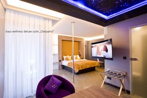 A hotel room with a bed, a TV, a purple chair, and a ceiling light. - PLAZA INN stays design Dortmund (Dortmund)